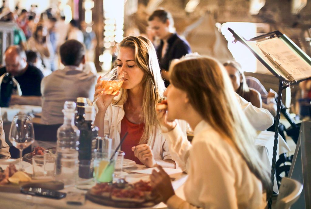 Friends dining in a cozy Italian restaurant, enjoying drinks and food in a lively atmosphere.