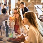 Friends dining in a cozy Italian restaurant, enjoying drinks and food in a lively atmosphere.