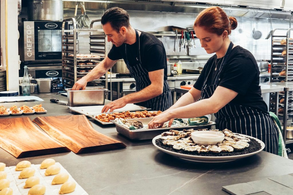 Two chefs working together in a professional kitchen, preparing gourmet dishes with precision.