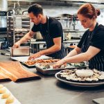 Two chefs working together in a professional kitchen, preparing gourmet dishes with precision.