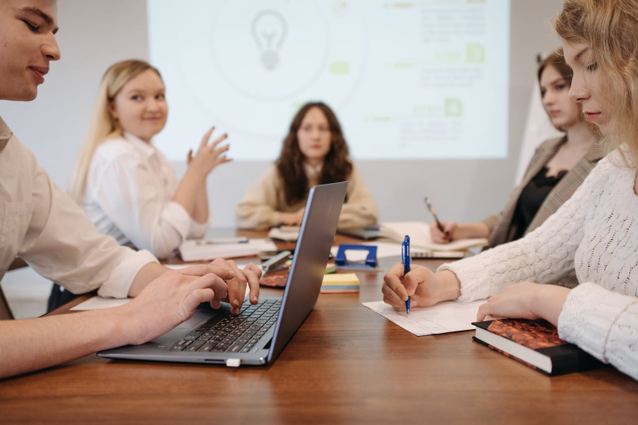 Young professionals having a meeting around a table with laptops and notes, showcasing teamwork.